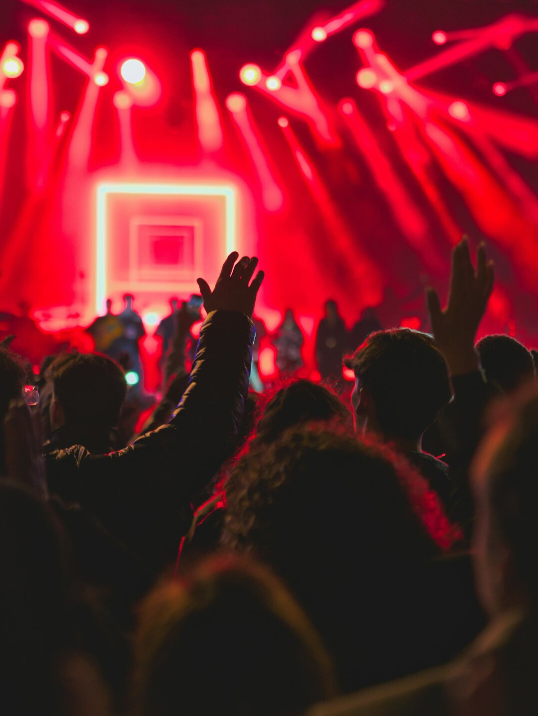 Concert crowd with raised hands under stage lights