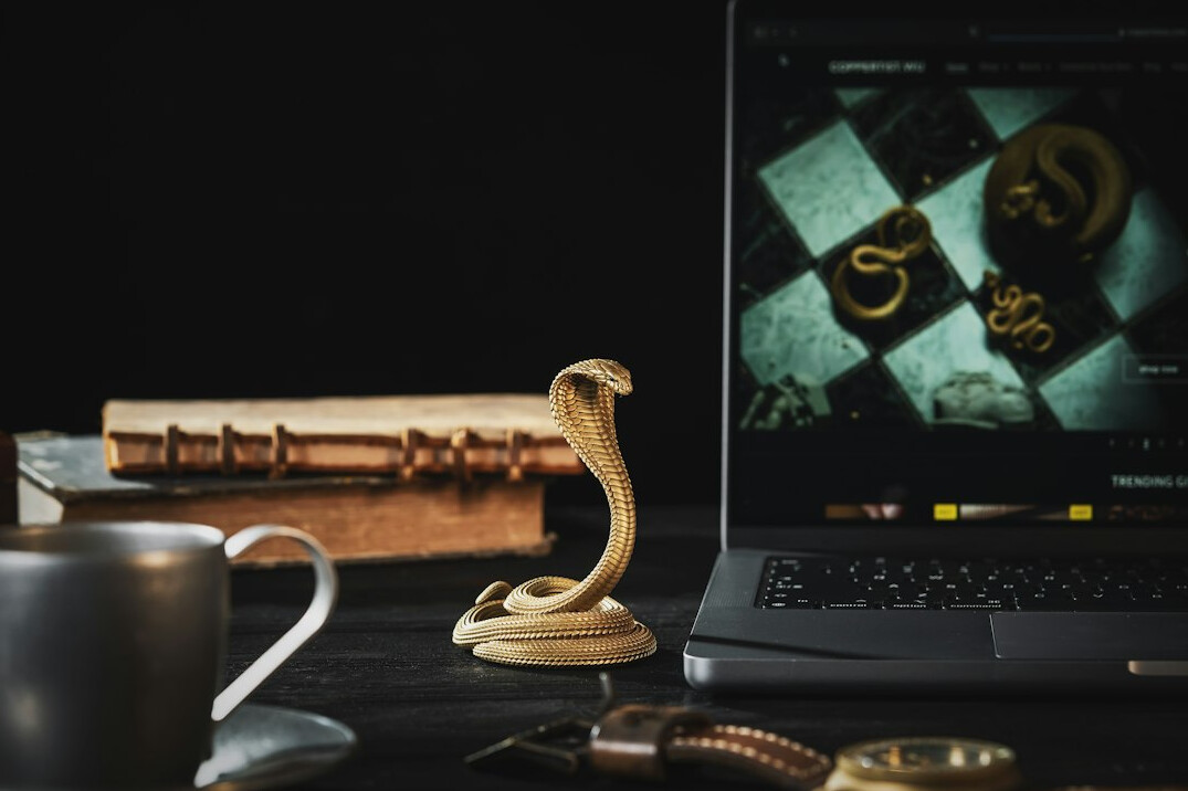 Laptop on a wooden desk with a notebook and a cup
