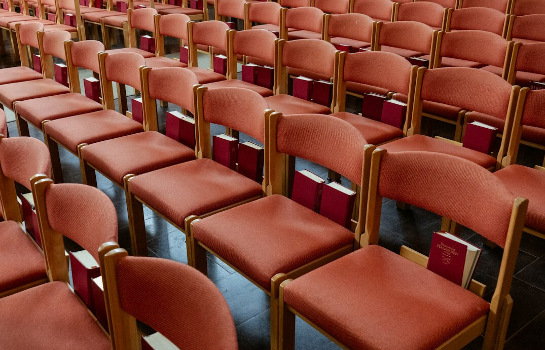 Rows of empty red theater seats in a dim auditorium